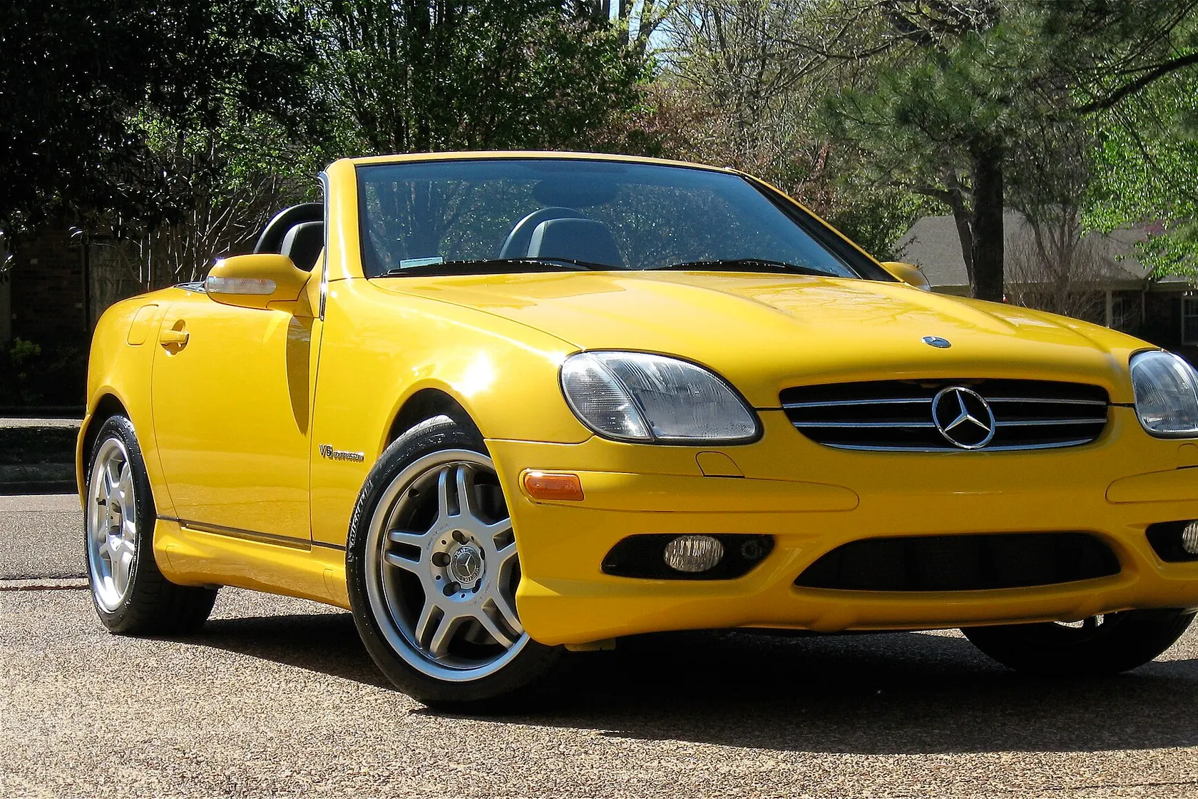 Yellow Mercedes-Benz SLK 32 AMG with its roof open, front three-quarter view