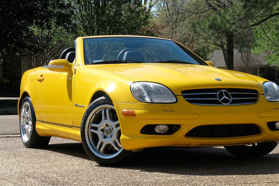Yellow Mercedes-Benz SLK 32 AMG with its roof open, front three-quarter view
