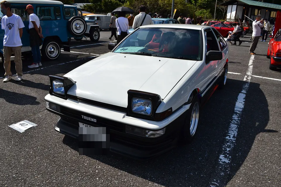 White and black Toyota Sprinter Trueno GT Apex AE86 in front three-quarter view